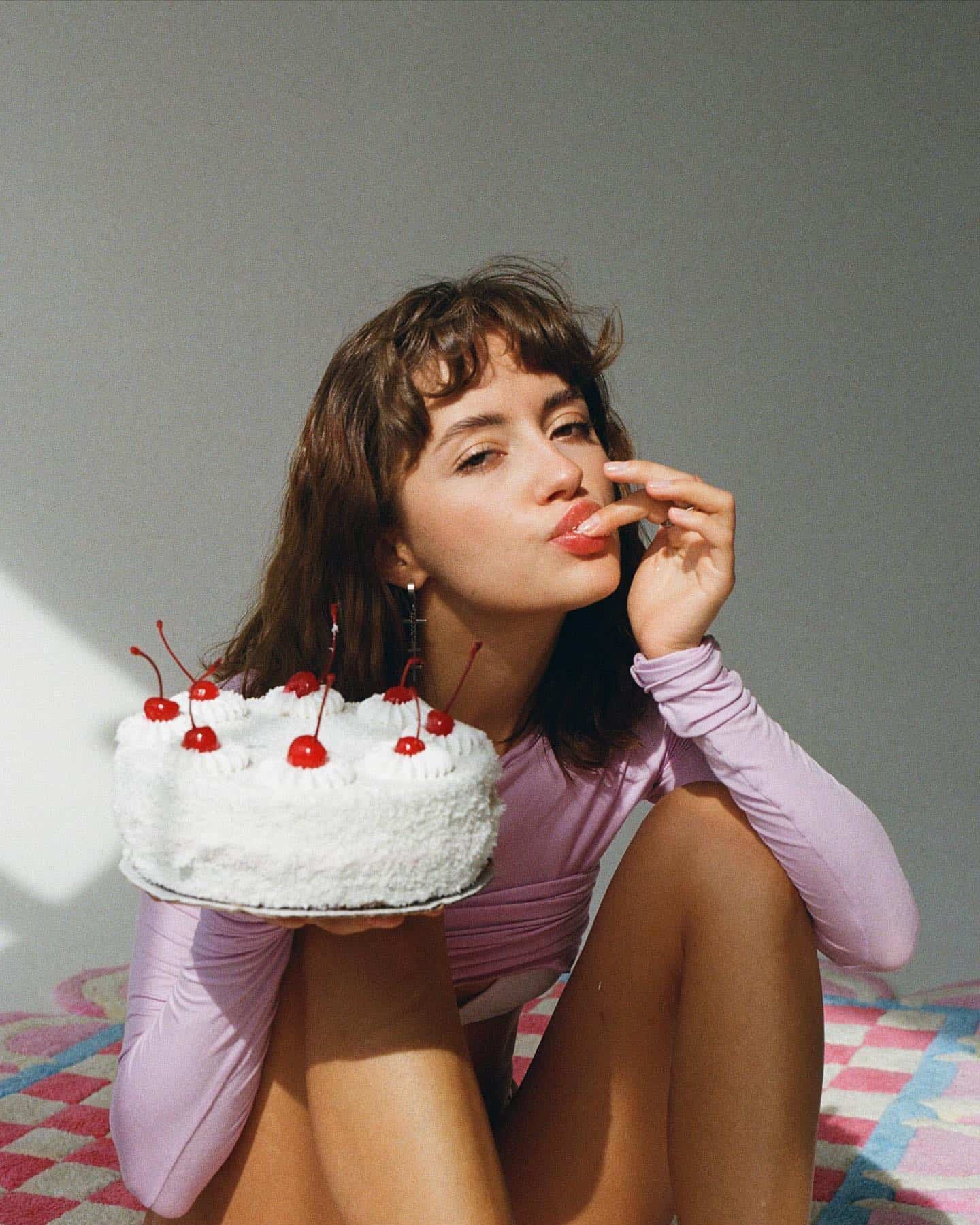 Vibrant Chinatown Amplify promotional image featuring trendy Asian-inspired fashion model holding a cherry-topped white cake, emphasizing cultural celebration, modern style, and community engagement.